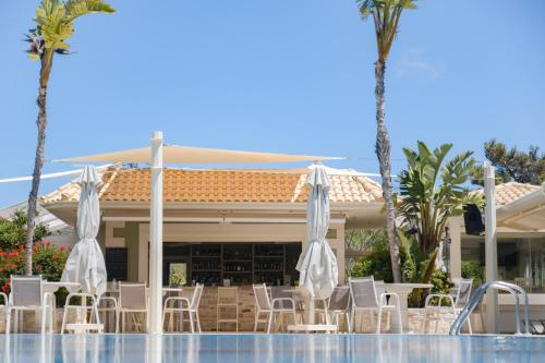 a pool with chairs and umbrellas in front of a resort at Philharmonie Hotel in Kalamaki Heraklion