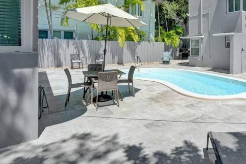 a table and chairs with an umbrella next to a pool at Retro Oasis by Las Olas in Fort Lauderdale