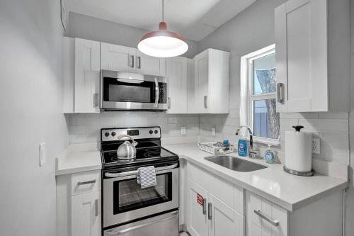 a white kitchen with a stove and a sink at Unique Las Olas Stay Pool Free Parking in Fort Lauderdale