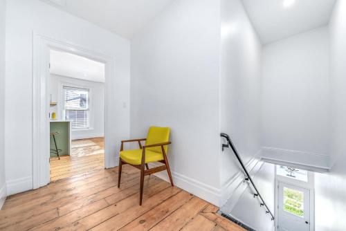 a yellow chair in a white room with a wooden floor at The Wellington General in Wellington