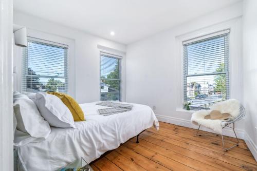 a white bedroom with a bed and two windows at The Wellington General in Wellington