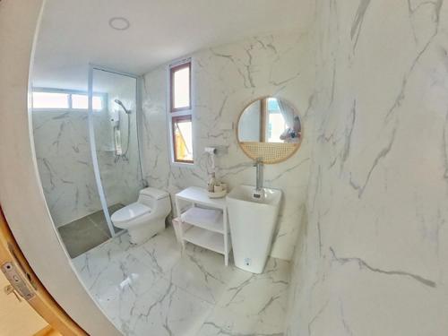 a white marble bathroom with a sink and a mirror at The3 Happiness Nordic Private Home in Nakhon Phanom