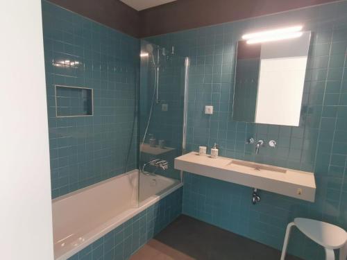 baño de azulejos azules con bañera y lavamanos en Galé T3 en Caloura