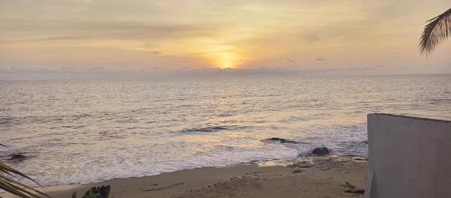 una puesta de sol en la playa con el océano en Résidence Callens, en Kribi