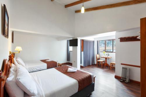 um quarto de hotel com duas camas e uma secretária em Hotel Amerinka em Cusco