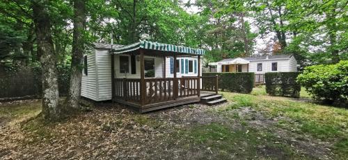 una pequeña casa con un porche en un patio en CAMPING ONLYCAMP LA VARENNE en Neung-sur-Beuvron