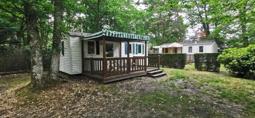 une petite maison avec un porche dans une cour dans l'établissement Camping Onlycamp De La Varenne, à Neung-sur-Beuvron