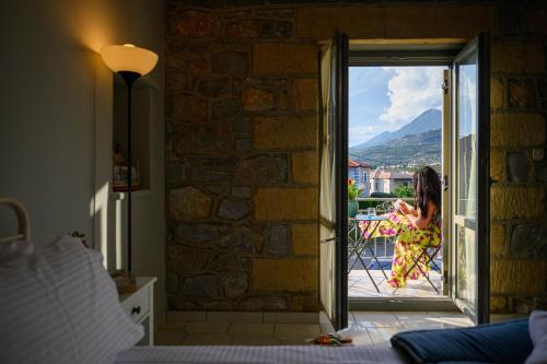 a woman standing on a balcony looking out the door at Μαϊστράλι in Kotrónion