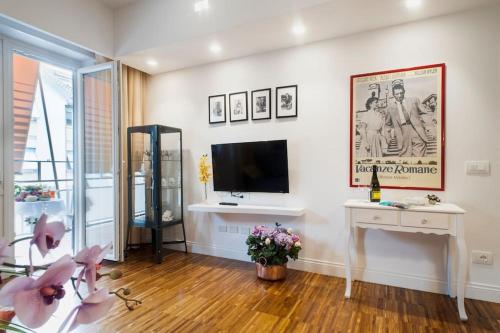 uma sala de estar com televisão e uma mesa com flores em Roma-Incantata Apartment em Roma