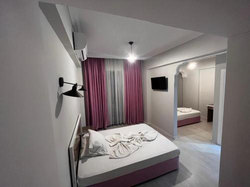 a small bedroom with a bed and a pink curtain at Best Alanya Hotel in Alanya