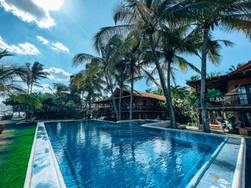 a swimming pool in front of a resort with palm trees at El Sitio de Playa Venao in Playa Venao