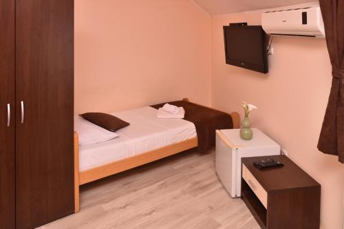 Cette petite chambre comprend un lit et une télévision. dans l'établissement Guest House Villa Mir, à Kragujevac
