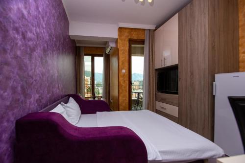 a bedroom with a bed with a purple wall at SunSea Apartments in Budva