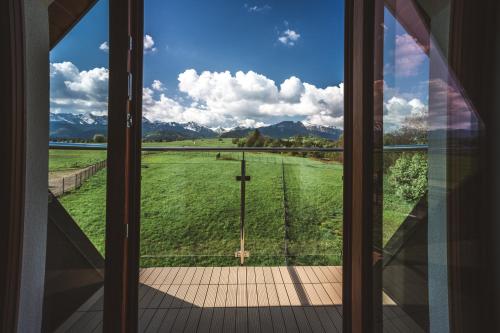 a window with a view of a field with mountains at Apartamenty Widok Tatr in Zakopane