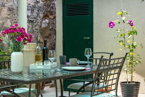 a table with chairs and a green door and purple flowers at Sweet Studio with terrace in Dubrovnik