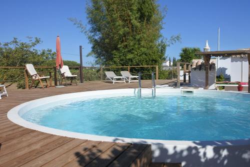 a large swimming pool on a wooden deck with chairs at Casa do Livramento in Luz de Tavira