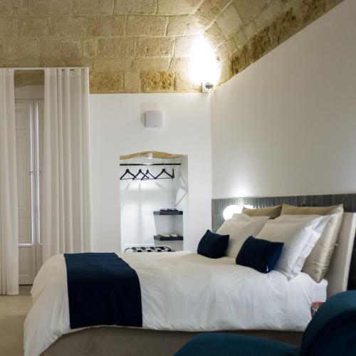 a bedroom with a large white bed with blue pillows at Casa Minerva - Suite e Relax in Gioia del Colle