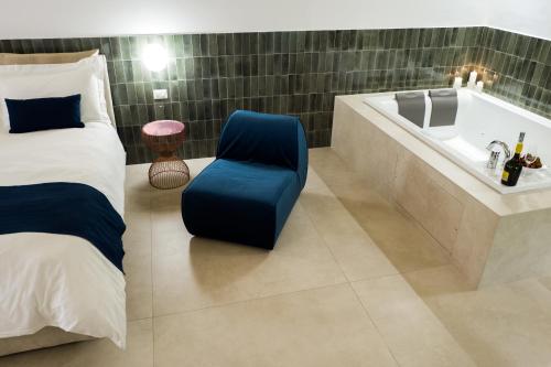 a bedroom with a tub and a bed and a chair at Casa Minerva - Suite e Relax in Gioia del Colle