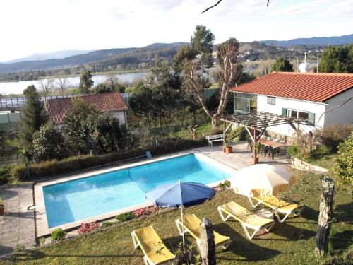 een zwembad met parasols en stoelen en een huis bij VNC13V4, encantadora casa e piscina, vista rio Min in Gondarém