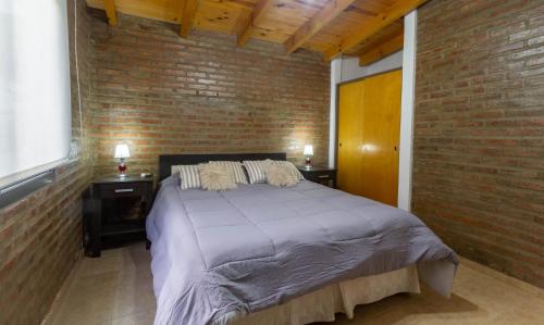 a bedroom with a bed and a brick wall at Cabañas Noscohue in Villa General Belgrano