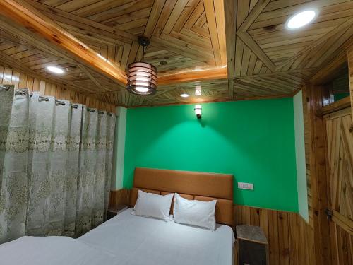 sypialnia z zieloną ścianą i łóżkiem w obiekcie Alpine Valley Homestay w mieście Shimla