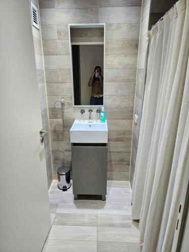 a person taking a picture of a bathroom with a sink at LaMari in Buenos Aires