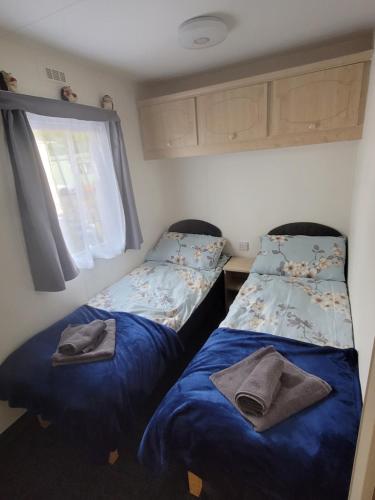 a bedroom with two beds with blue sheets and a window at The Sunny Bunny Holiday Home in Ballantrae