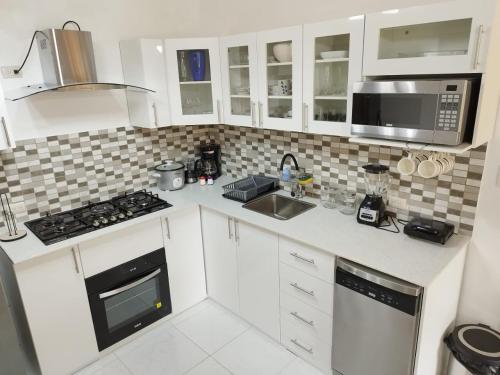 a kitchen with white cabinets and a stove and microwave at Cabaña de Elsa in Olón