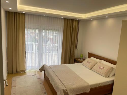 ein Schlafzimmer mit einem Bett mit zwei Kissen und einem Fenster in der Unterkunft Apartment Emina Free Garage Parking in Sarajevo