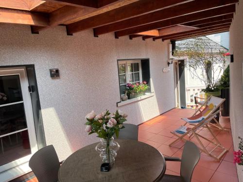 un vase de fleurs sur une table sur une terrasse dans l'établissement Le Terrier du Katz, à Dabo