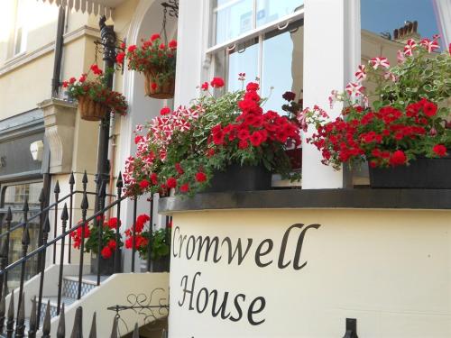 a sign on a house with red flowers in a window at Cromwell House in Eastbourne