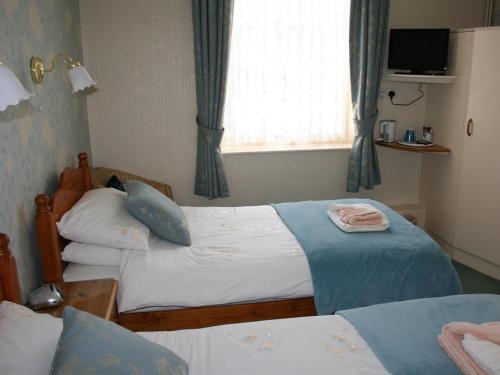 a bedroom with two twin beds and a window at Cromwell House in Eastbourne