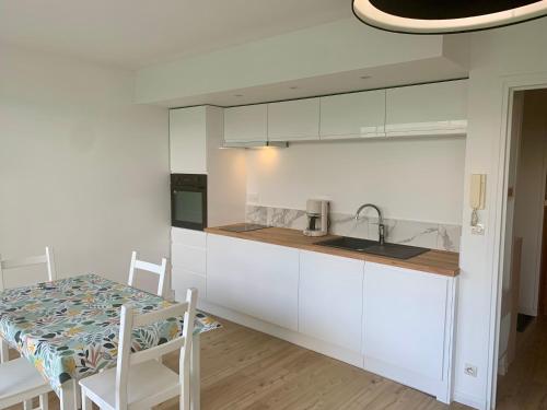 une cuisine avec des armoires blanches, une table et un évier dans l'établissement Studio cosy cinq personnes, à Le Touquet-Paris-Plage