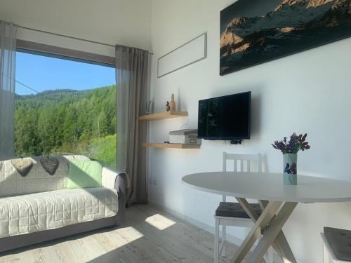 ein Wohnzimmer mit einem Sofa, einem Tisch und einem TV in der Unterkunft B&B Tantané in Torgnon