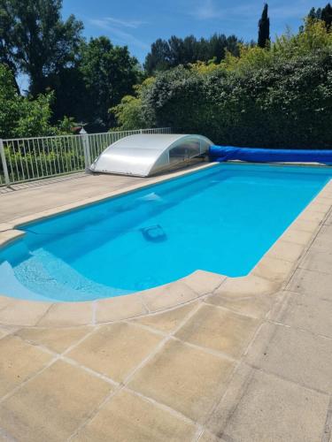 a blue swimming pool with a solar device in a yard at Charmant petit havre de paix in Dauphin