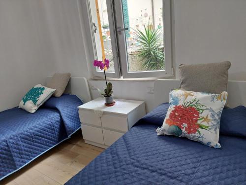 sypialnia z 2 łóżkami z niebieską pościelą i oknem w obiekcie DA me MAE w mieście La Spezia