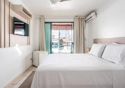 Un dormitorio con una gran cama blanca y una ventana en Pousada Enseada dos Golfinhos, en Bombinhas