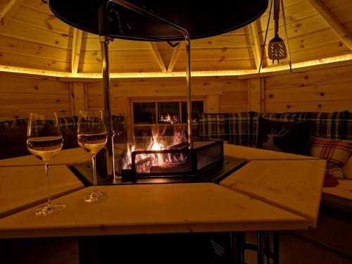 two glasses of wine on a table with a fireplace at Salzgeber Appartements in Sankt Gallenkirch