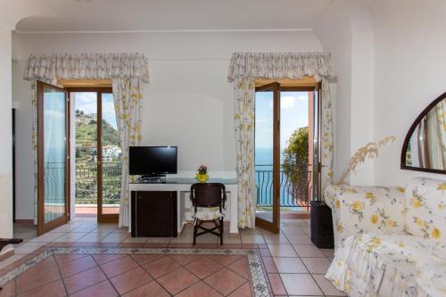 a living room with a couch and a desk with a television at Fico D'India Relais in Furore