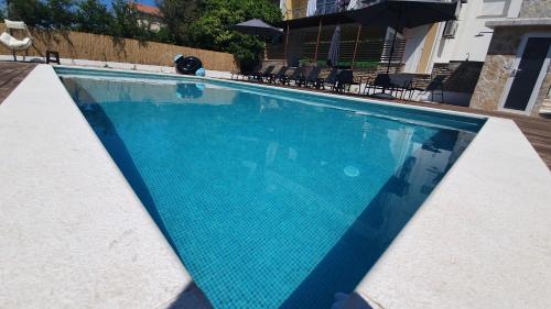 a blue swimming pool with chairs and an umbrella at Apartments Meštrović with heated swiming pool- near Split in Kaštela