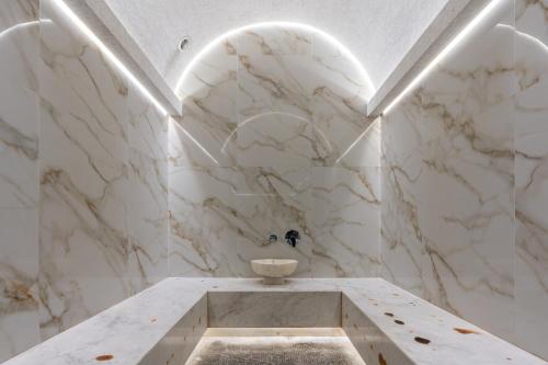 ein Bad mit weißen Marmorwänden und einem Waschbecken in der Unterkunft MODERNO Hotel in Taschkent