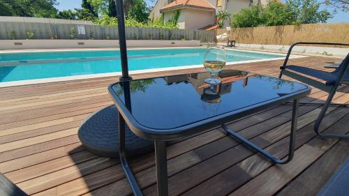 a glass table with a glass of wine sitting next to a pool at Apartments Meštrović with heated swiming pool- near Split in Kaštela