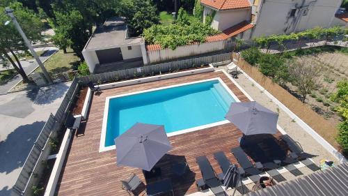 an overhead view of a swimming pool with umbrellas at Apartments Meštrović with heated swiming pool- near Split in Kaštela