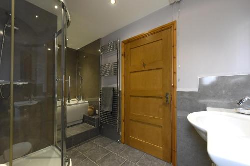 a bathroom with a shower and a sink and a door at Tranquil Cornish retreat close to Port Isaac beaches and moor in Bodmin