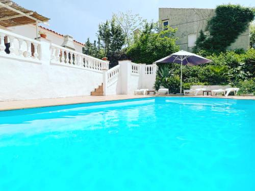 - une piscine bleue avec un parasol et des chaises dans l'établissement Villa Mas Blau Munt, à Lloret de Mar