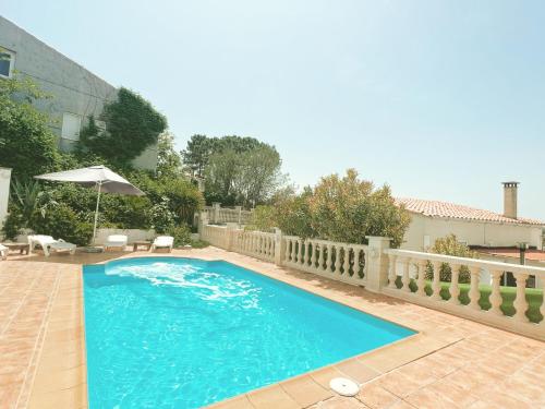 une grande piscine bleue avec un parasol et des chaises dans l'établissement Villa Mas Blau Munt, à Lloret de Mar