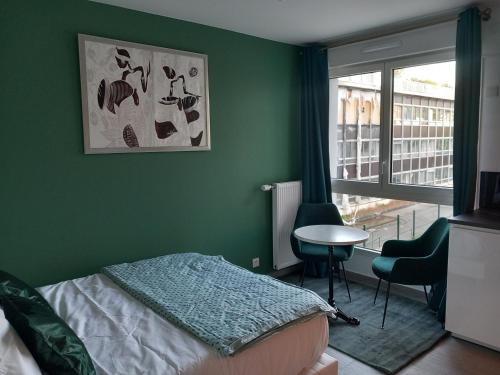 a bedroom with a green wall with a bed and a window at Le Cocon Vert in Rueil-Malmaison