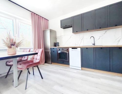 a kitchen with blue cabinets and a table with pink chairs at APARTAMENTY Charzykowy in Charzykowy