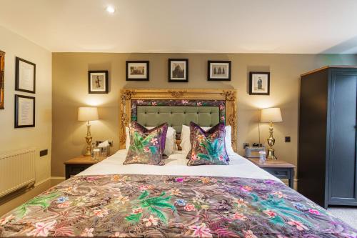 a bedroom with a large bed with colorful pillows at The George Hotel, Amesbury, Wiltshire - The Coaching Inn Group in Amesbury