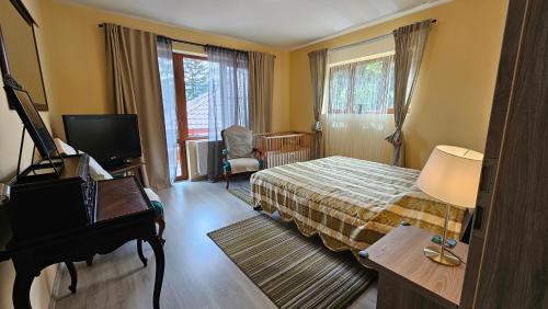a bedroom with a bed and a piano and a television at Kalinderu SKIER'S APARTAMENT BELLEVUE in Buşteni